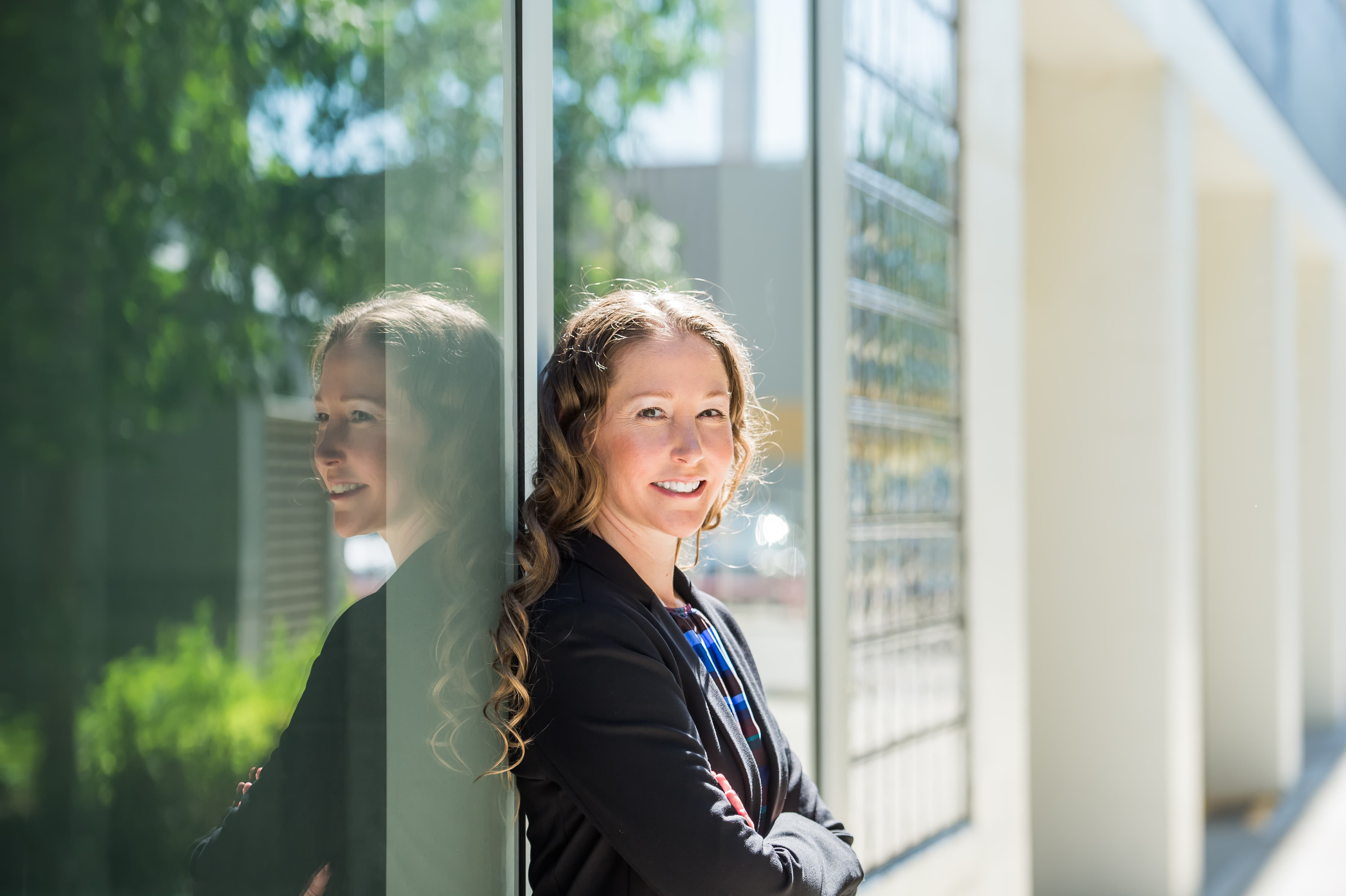 Dr. Tricia Sandham standing in front of glass building